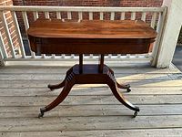 Full view of closed mahogany games table on porch