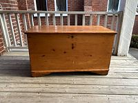 Front view of pine blanket chest showing lid, front panel, and bracket feet