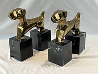 Front three-quarter view of both brass dog bookends on marble bases