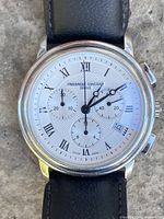 Front view showing dial with Roman numerals, three sub-dials, date window, leather strap attachment