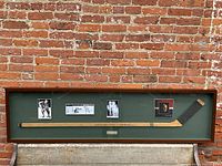 Full view of framed shadow box with stick, photos and plaque