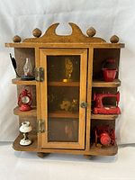 Front view of wooden cabinet with miniatures on shelves