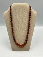 Full necklace on display bust showing graduated amber beads