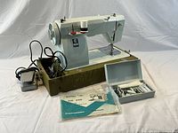 Sewing machine on base with foot pedal, cords, accessory box, manual