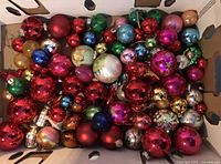 Open box filled with assorted coloured glass Christmas ornaments