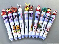 All ten novelty Christmas multi-ink pens lined up showing toppers and barrels