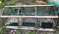 Full view of entire wooden lobster trap showing slat construction, green netting and entry chambers