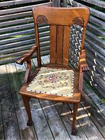 Front view of oak armchair showing carved crest, arms, needlepoint seat