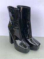 Front three-quarter view of both boots showing patent finish, block heels, square toes