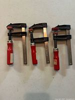 Three identical F-style bar clamps laid out on table