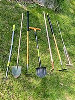 Seven garden tools laid out on grass