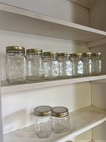 Seven mason jars lined on shelf, showing varying heights and lids