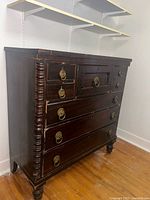 Front view showing all drawers, brass pulls, turned feet