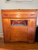 Front view of antique wooden buffet showing glass door, drawer, carved details