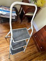 Full view of folded three-step stool showing frame and handle