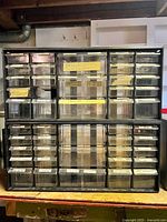 Front view of black multi-drawer cabinet showing all drawers and labels