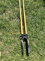 Full view of post hole digger lying on grass