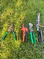 All four garden cutting tools laid out on grass
