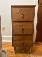 Front view showing three drawers, knobs, and legs