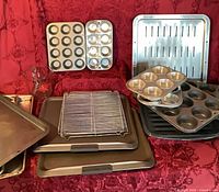 Group of muffin pans, cookie sheets, cooling rack, measuring cup
