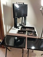 four folded black tables on stand, trays displayed
