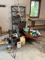 Overview of entire gardening lot showing wheelbarrow, tools, shelving, crocks