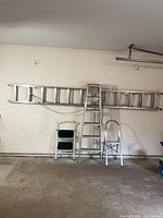 Full view of extension ladder on wall with other ladders in front