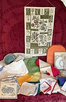 Full view of assorted linens on red background including tea towel, placemats, napkins and crocheted pieces