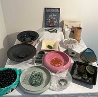 Overall view of vases, bowls, frogs, marbles, book and scissors on table