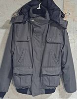 Front view of grey Nobis Cartel bomber jacket showing pockets, hood and overall condition