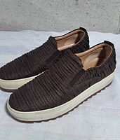 Side view of both loafers showing textured canvas uppers, white midsole, brown outsole