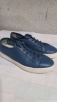 Left side view of blue perforated leather sneakers on white background