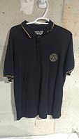 Front view of black Versace Jeans Couture polo on hanger