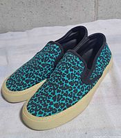 Left side view of both sneakers showing leopard canvas and rubber sole