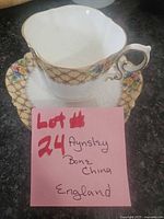 Teacup on saucer front view showing floral lattice band and gold trim