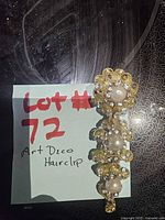 Full view of gold-tone hair clip beside lot note