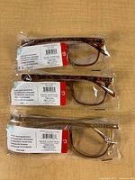 Three sealed eyeglasses in plastic sleeves on table