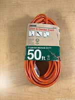 Front view of coiled orange extension cord with Woods packaging