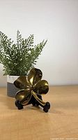 Front view of gold-tone clover on stand