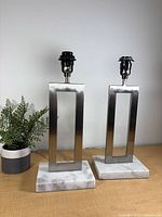 Front view of both brushed nickel open-frame lamp bases on marble bases