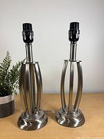 Front view of two brushed nickel open-cage lamp bases on round platforms