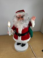 Full view of Santa figure on base holding lighted candle