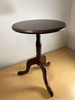 Full view of table showing round top, pedestal base, three legs