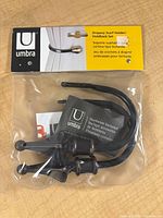 Front of sealed package showing two metal holdbacks and Umbra branding