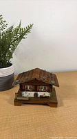 Front view of wooden Swiss chalet music box showing painted shutters and base