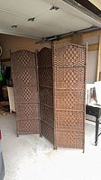 Full view of three-panel dark brown wicker room divider standing partially folded