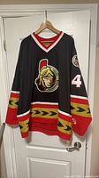 Front view of black Senators jersey with crest and chevron trim