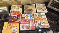 All seven cookbooks laid out on countertop showing covers and condition