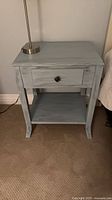 Front view of one painted nightstand showing drawer with fish knob and shelf