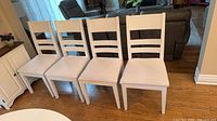 Front view of four white ladder-back chairs in a row